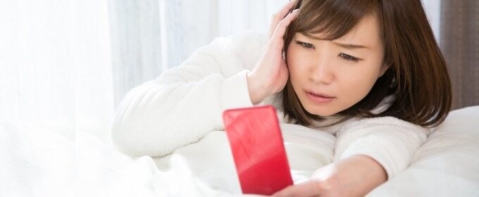 スマホを見ながら悩んでいる女性